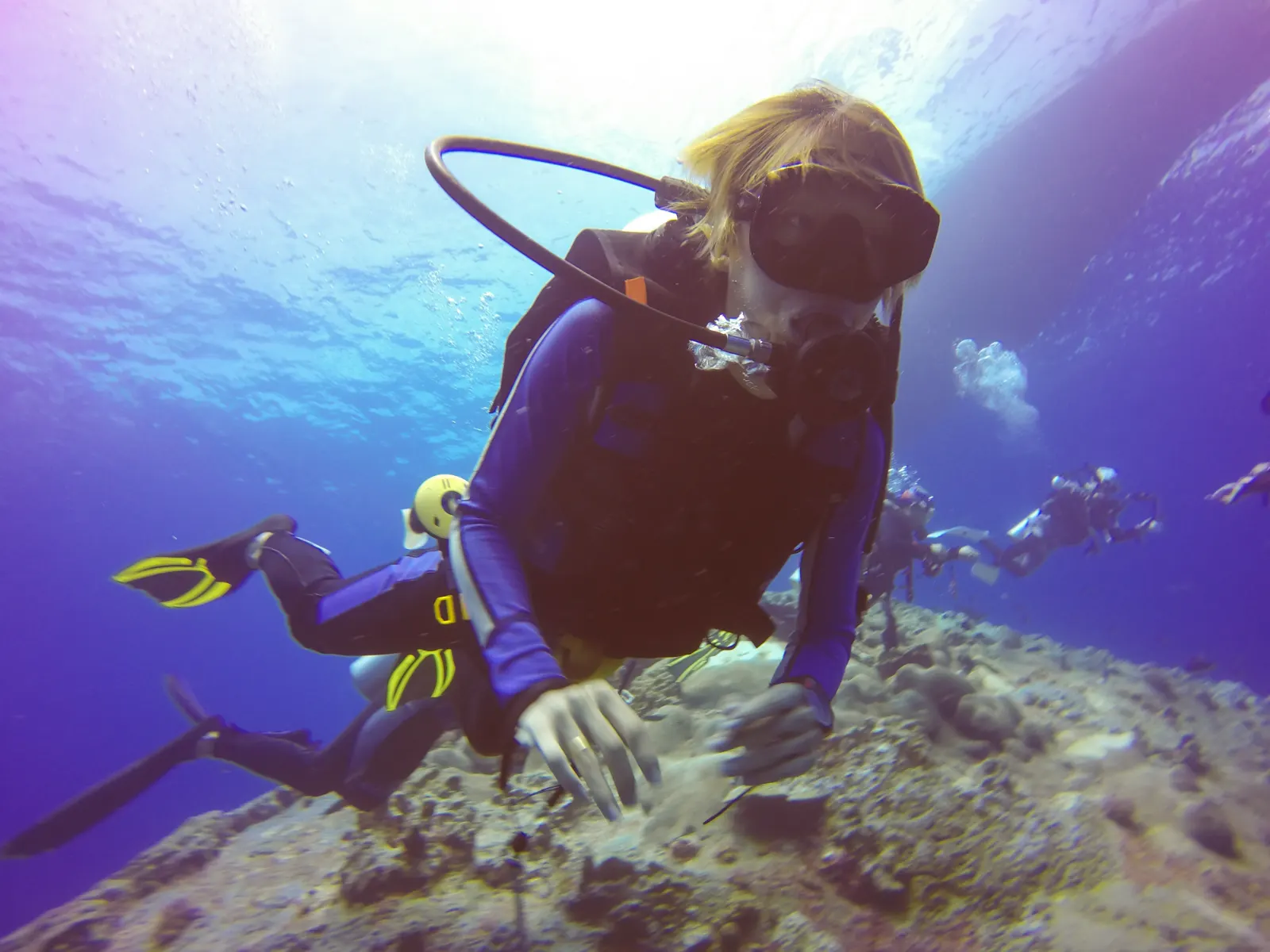Scuba diver swimming over a coral reef in clear blue water